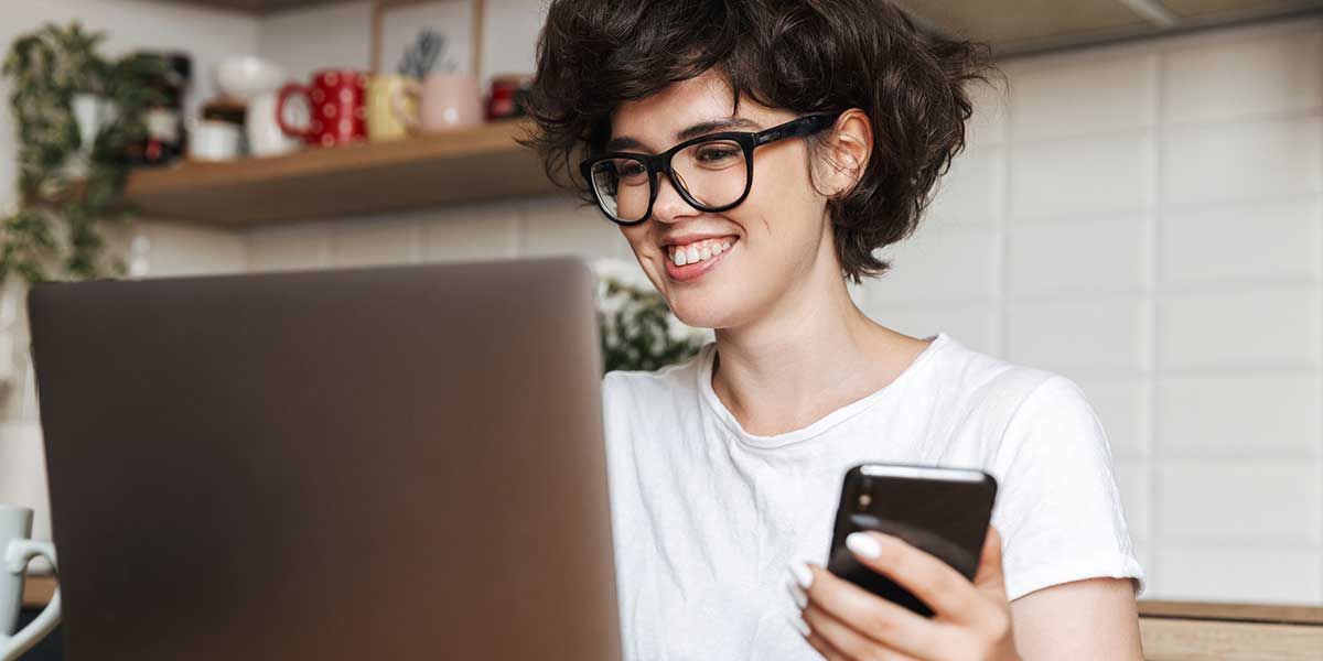 A woman smiling in front of a laptop.